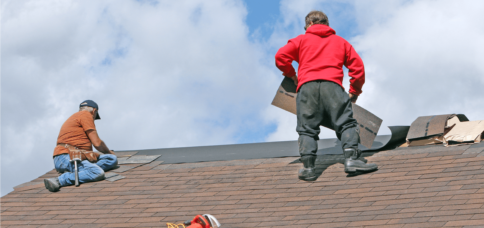 Workers repairing a roof under blue sky